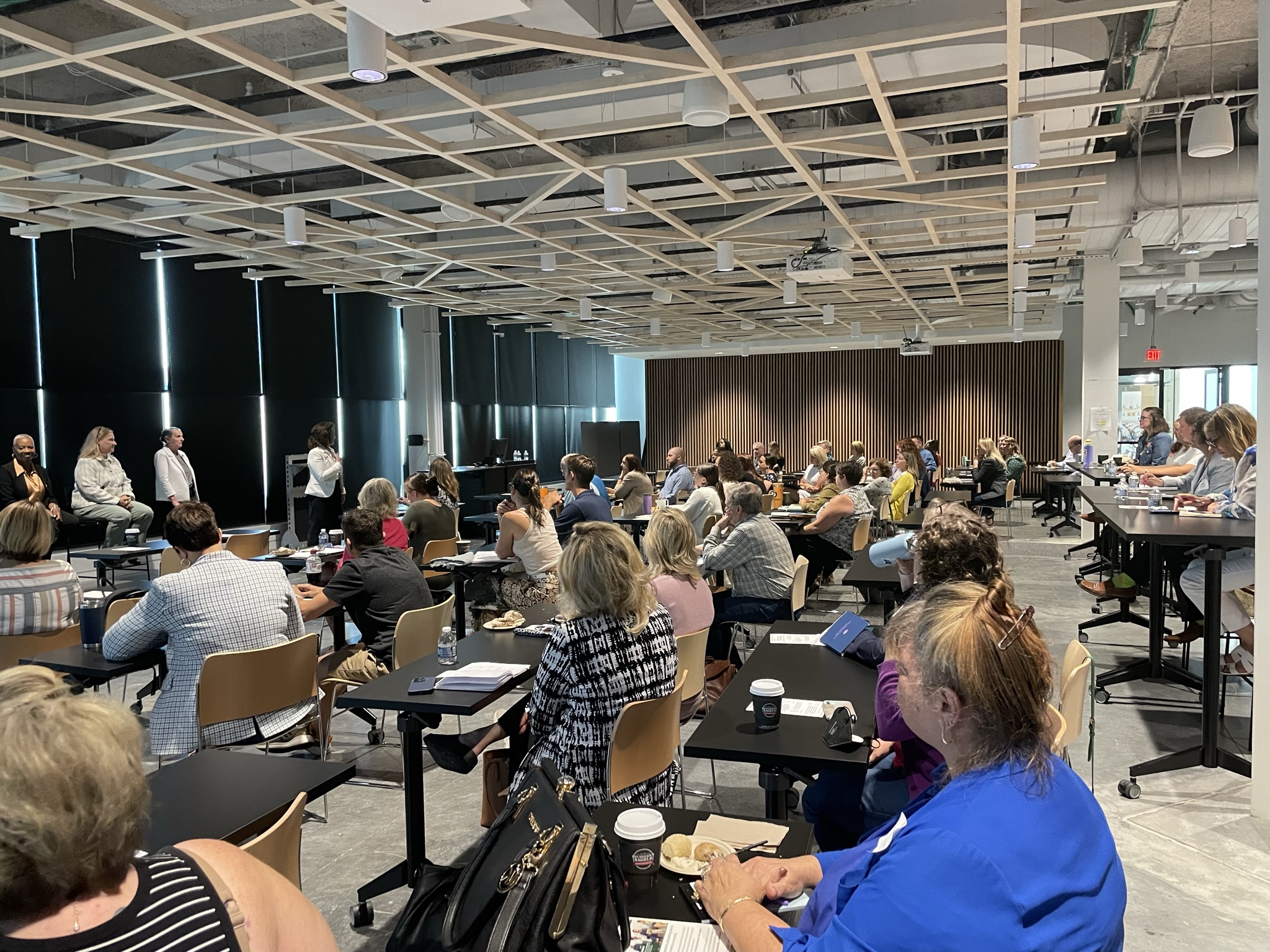 image of audience with four speakers up front